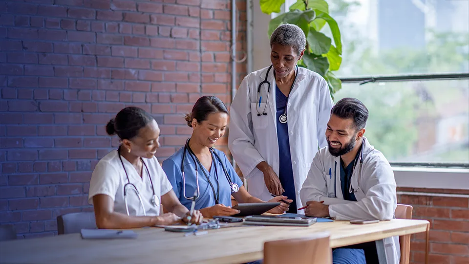 a group of four healthcare workers seated at a table having a conversation